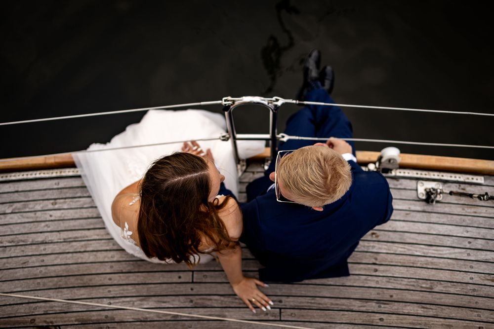 A couple lying on a wooden dock by the water in romantic poses.