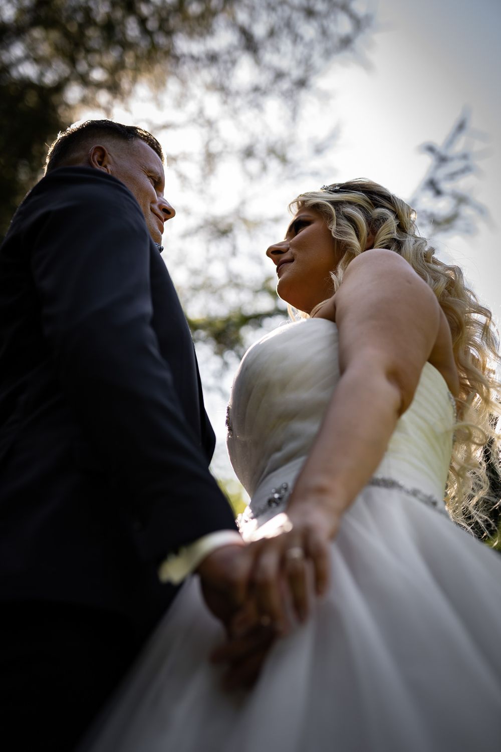 Low-angle wedding photography shots against bright sky.
