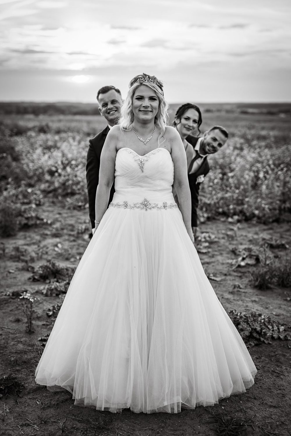 Black and white wedding portraits in an open field with dramatic sky.