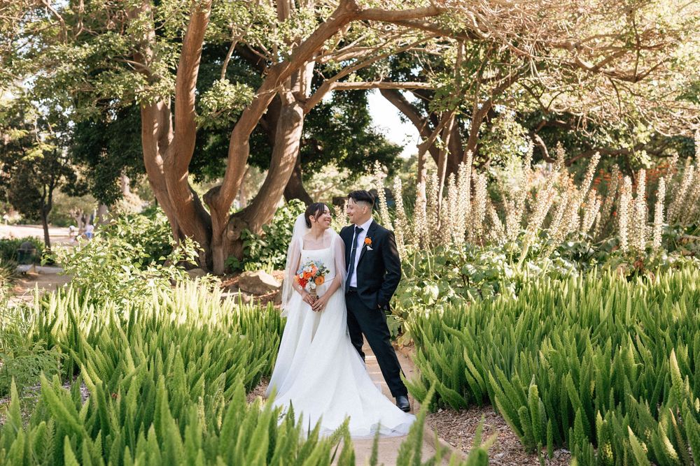 Detailed digital portrait of the couple smiling in the sunlight at Alice Keck Memorial Garden, showcasing the lush foliage.