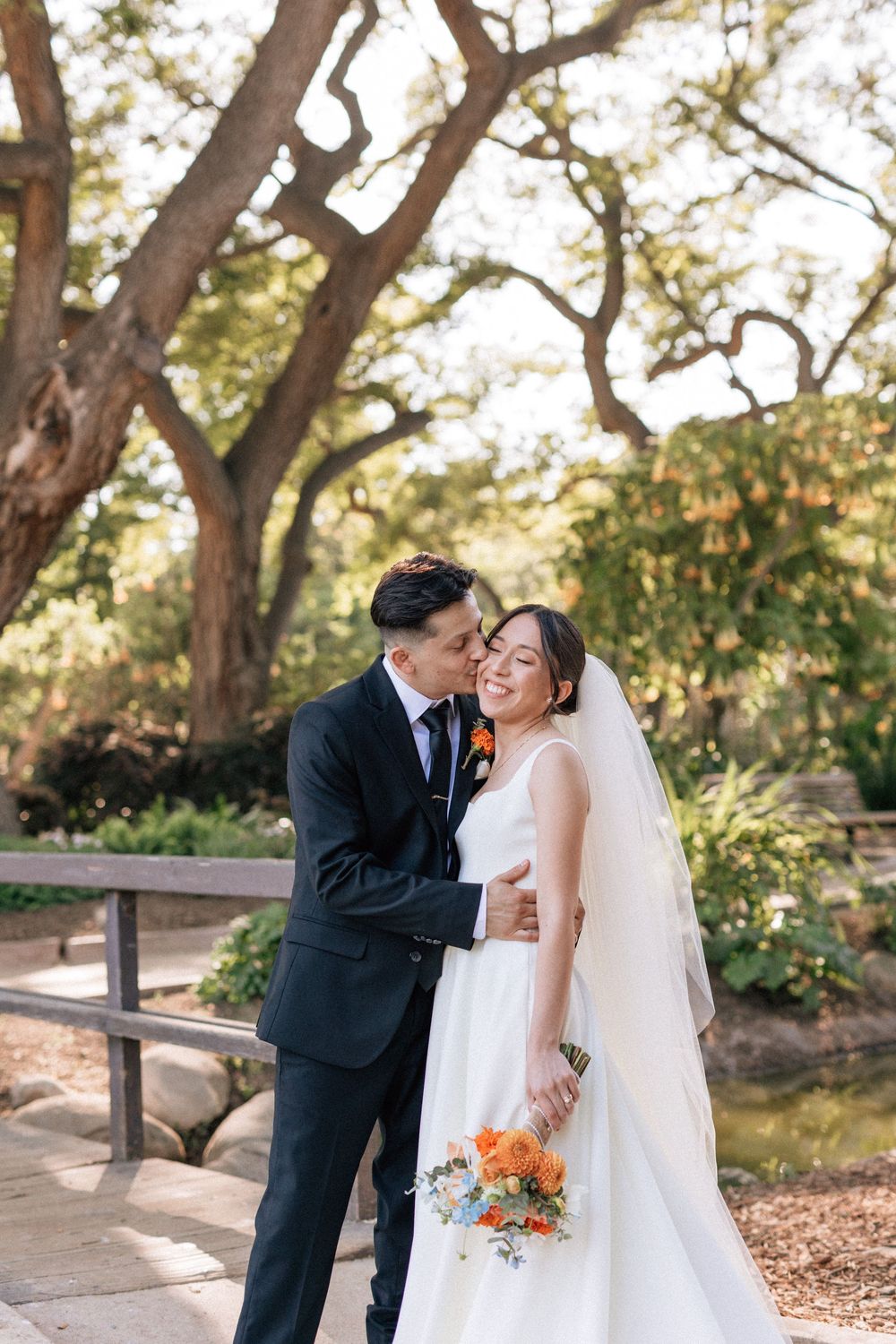 Colorful Santa Barbara wedding photographer captures the groom kissing the bride's cheek in a sunset moment in Santa Barbara.