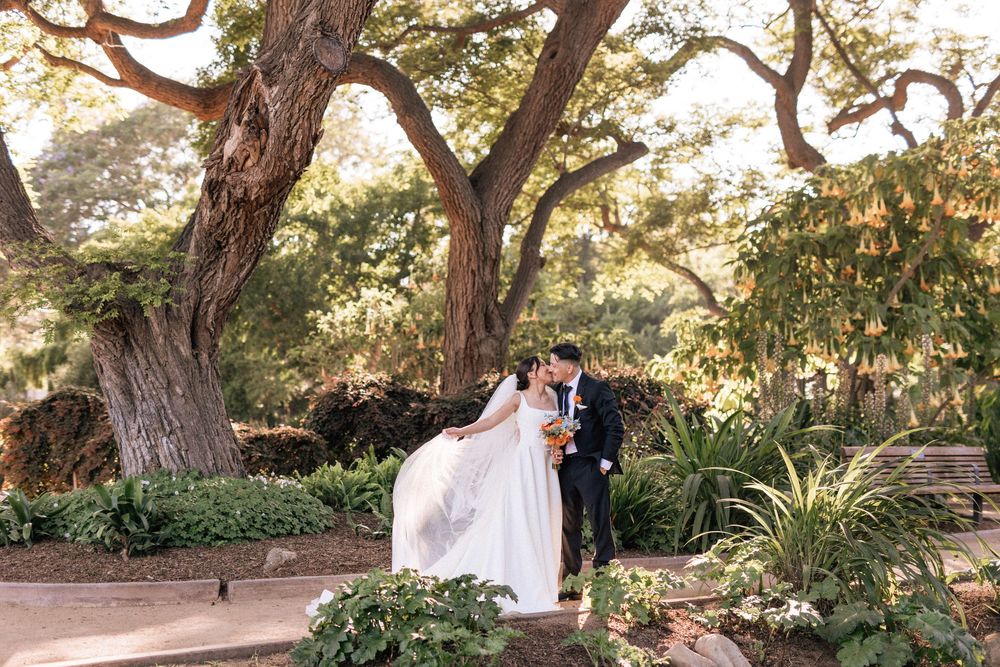 A bride in a garden at Alice Keck Memorial Park and Garden shows off her wedding dress and veil in a romantic sunset photo.