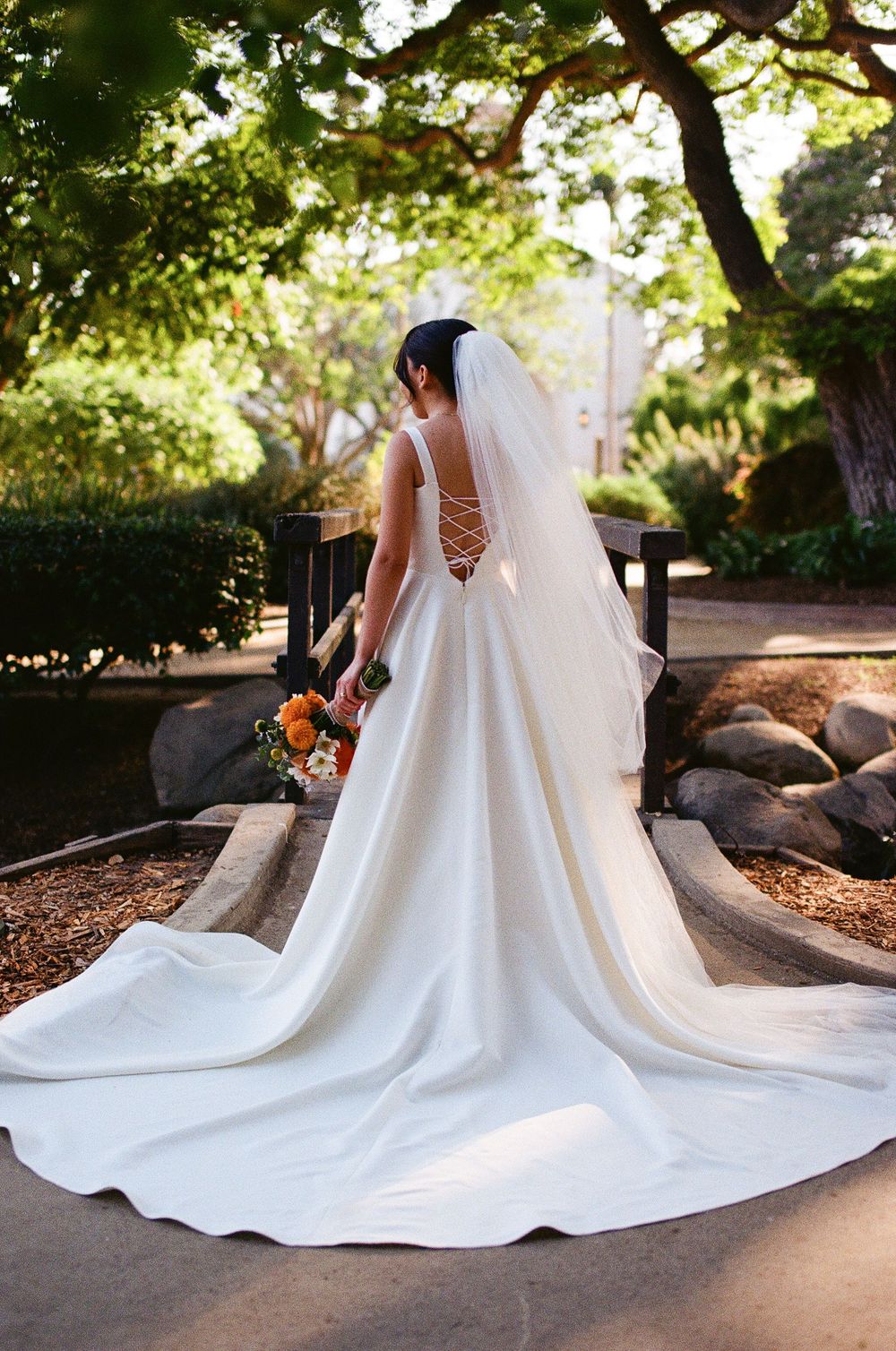 Dramatic photo of a bride on 35mm film with a cathedral length veil in Alice Keck Memorial Park Garden.
