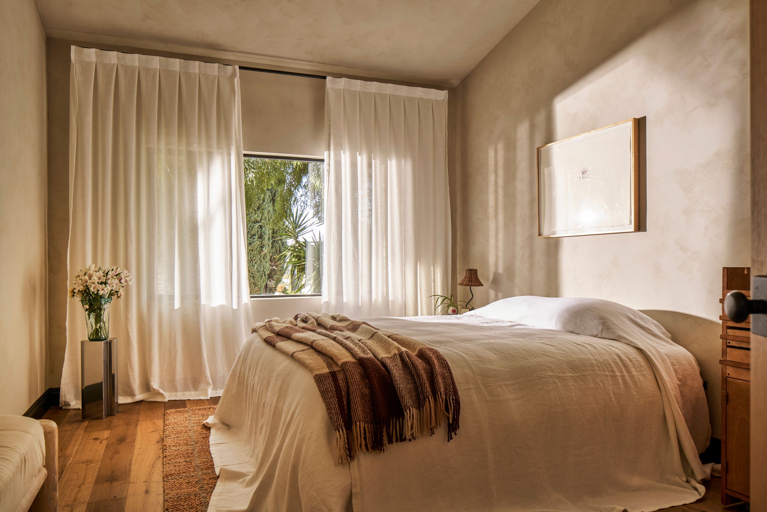 A panoramic view of a modern minimalist bedroom with white curtains and wooden floors in natural light.
