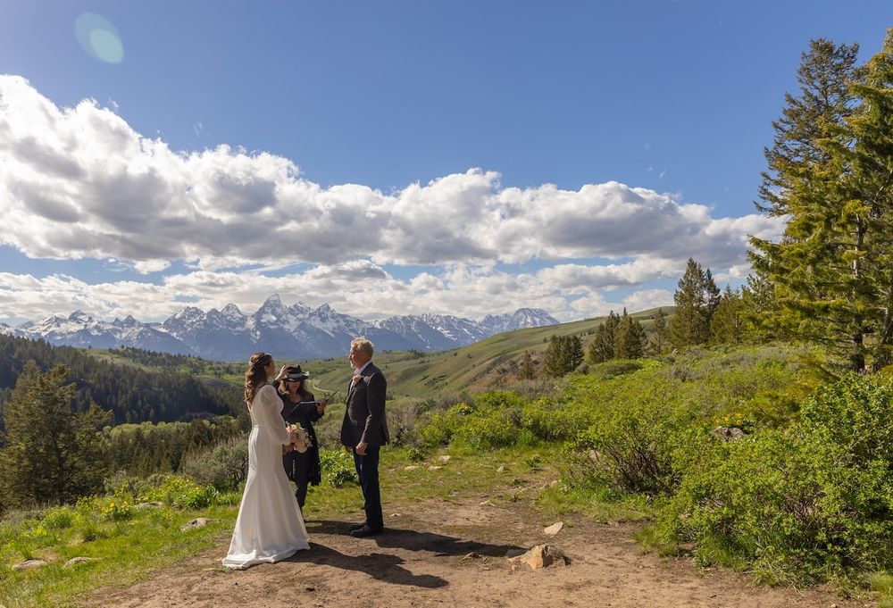 Scenic mountain wedding ceremony takes place on a hilltop overlook with dramatic mountain vistas in the background.