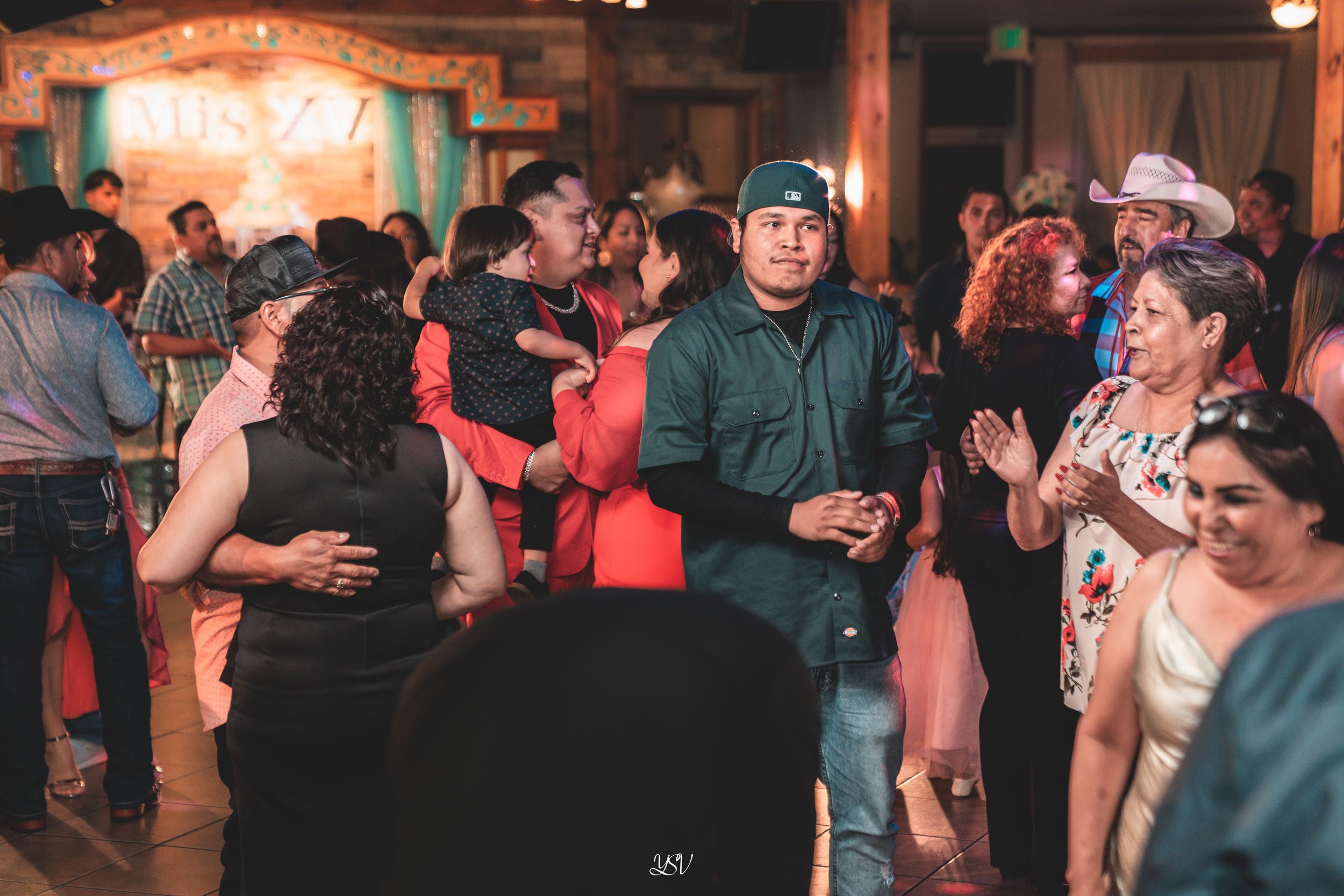 Couples dancing together at a dimly lit social dance event with warm lighting and rustic brick walls in the background.