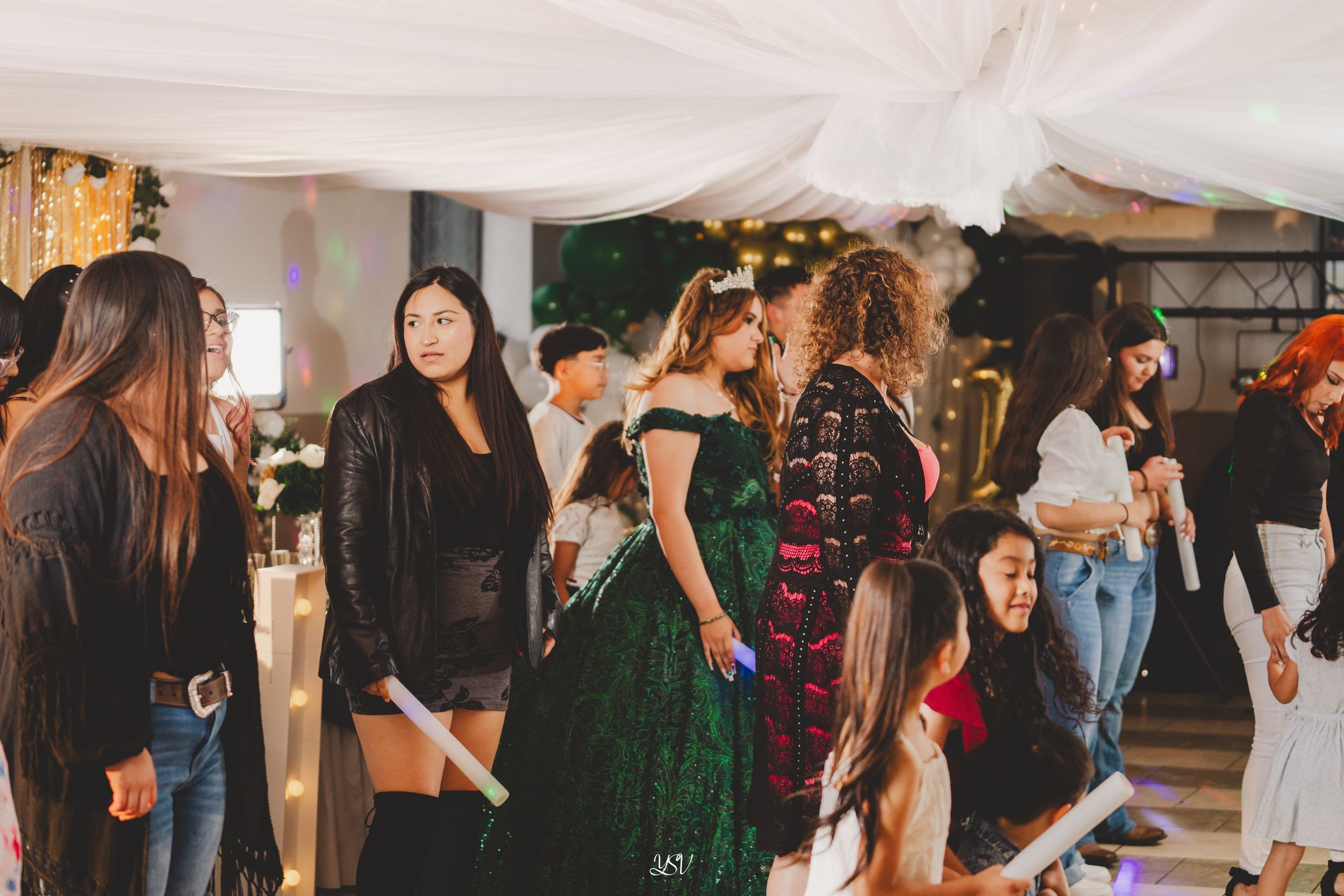 A lively party scene with people dancing and socializing in a dimly lit indoor venue.