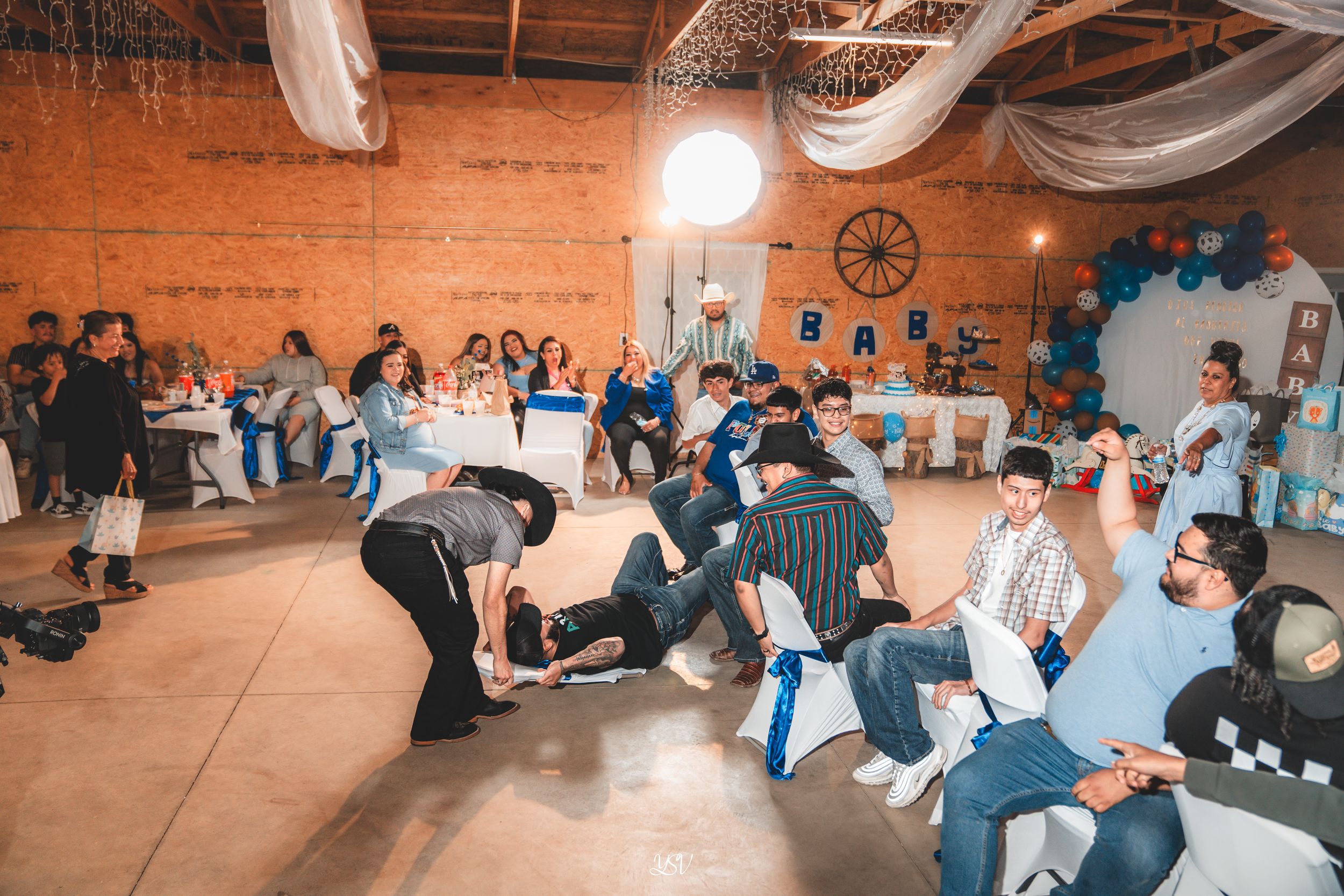 Students sit in rows on the floor during a group learning session in an industrial-style space with brick walls.
