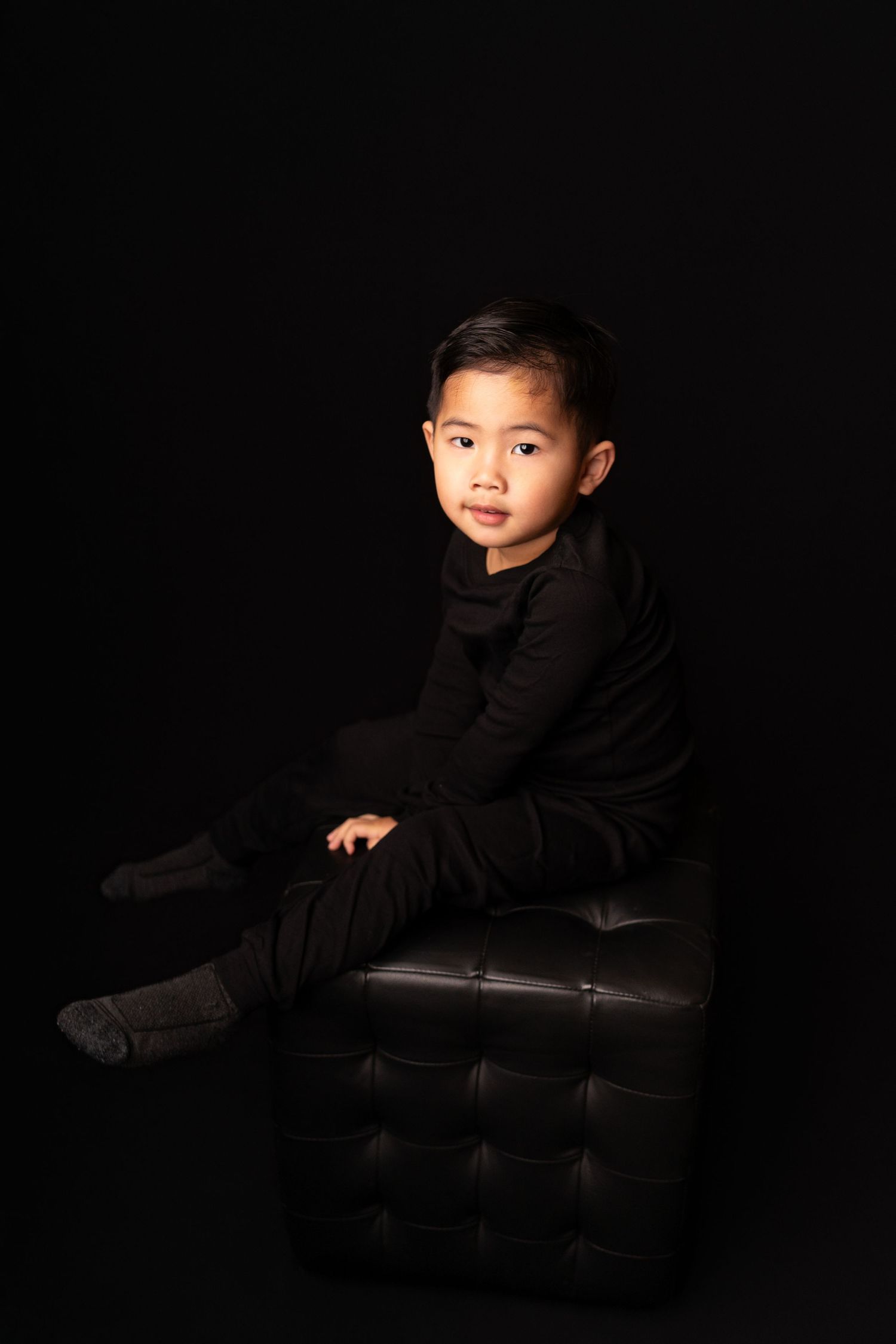 Dramatic low-key portraits in black clothing against a dark background.