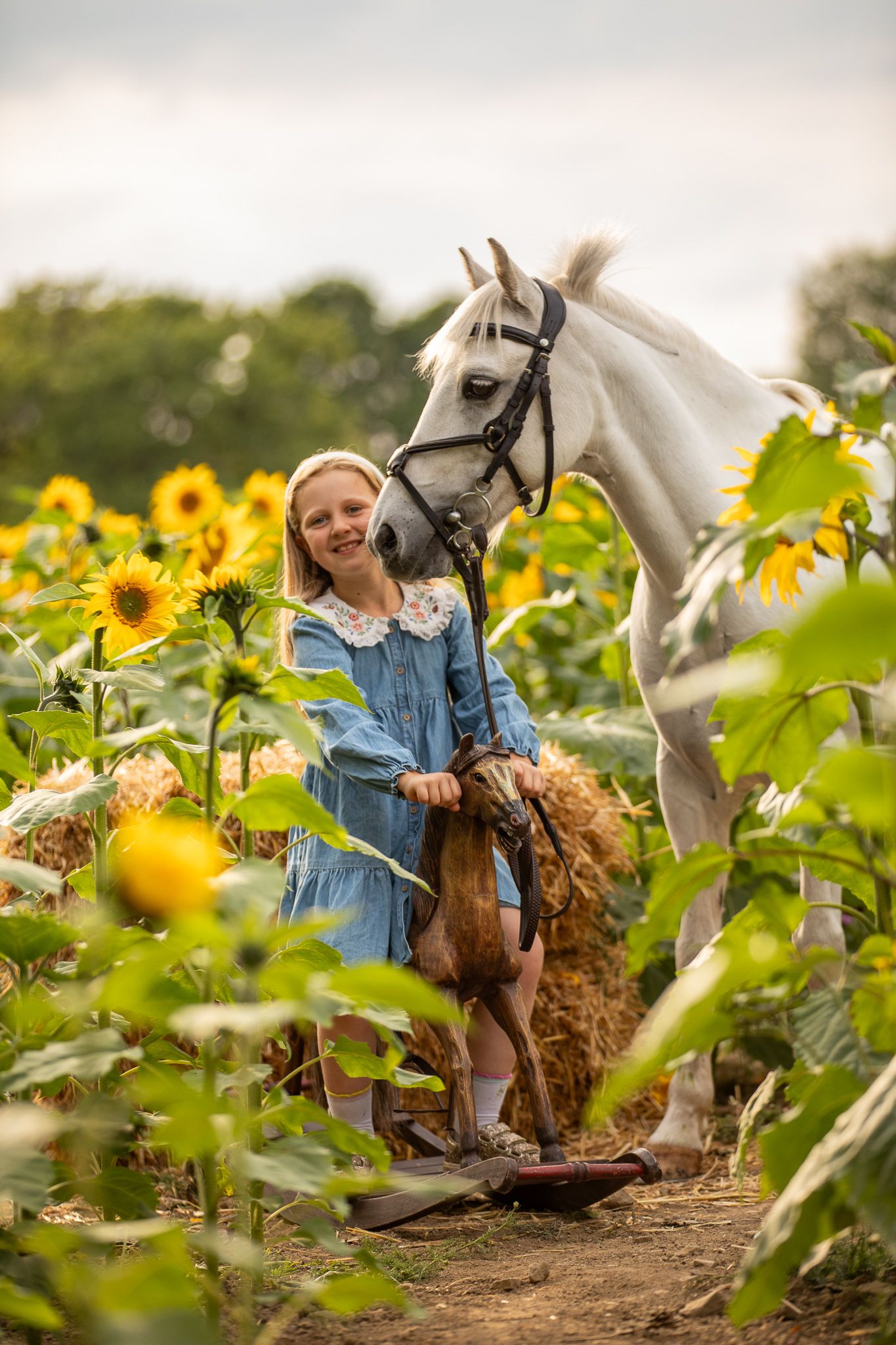 Young equestrian poses with palomino pony in a series of natural outdoor portraits showing their special bond.