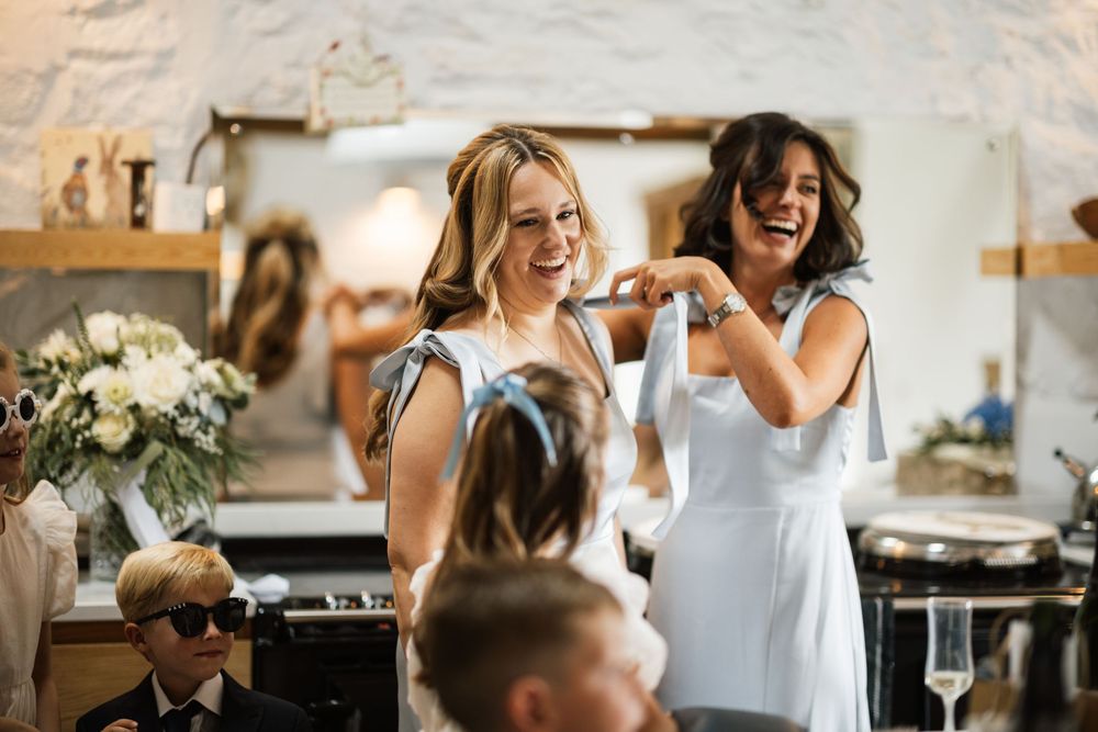 Candid moments of wedding party preparations show joyful laughter and celebration in a bright indoor setting.