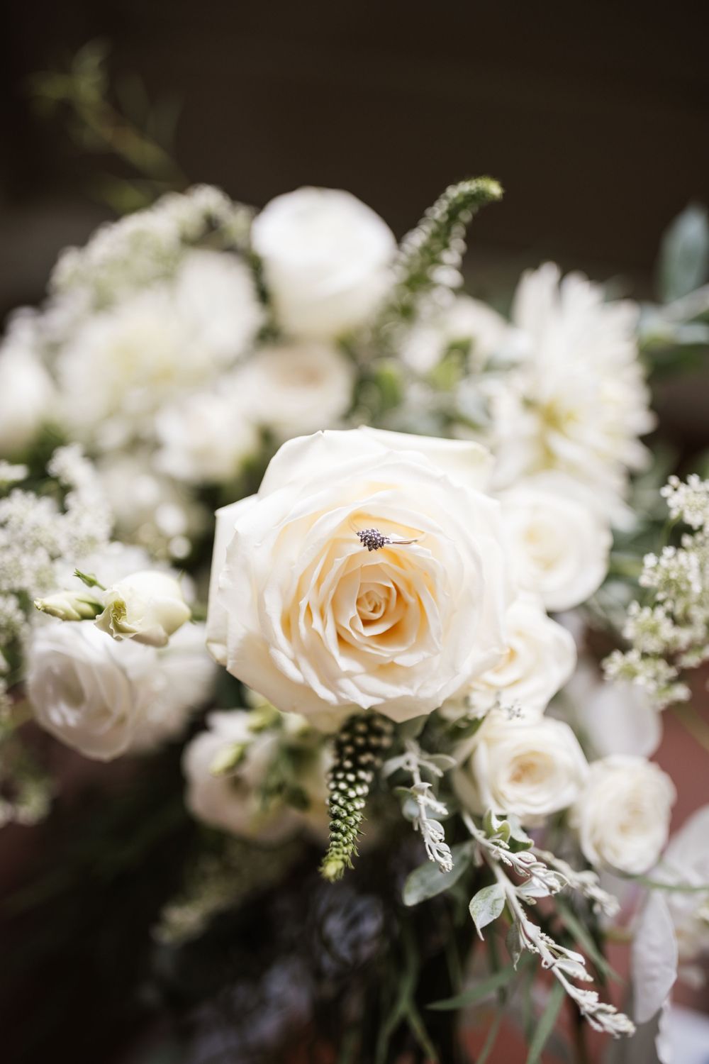 A row of delicate peach and white roses with baby's breath arranged in a soft, romantic wedding floral composition.