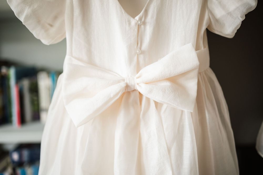 Close-up details of delicate white lace trim on a flowing wedding dress hem against a dark background.