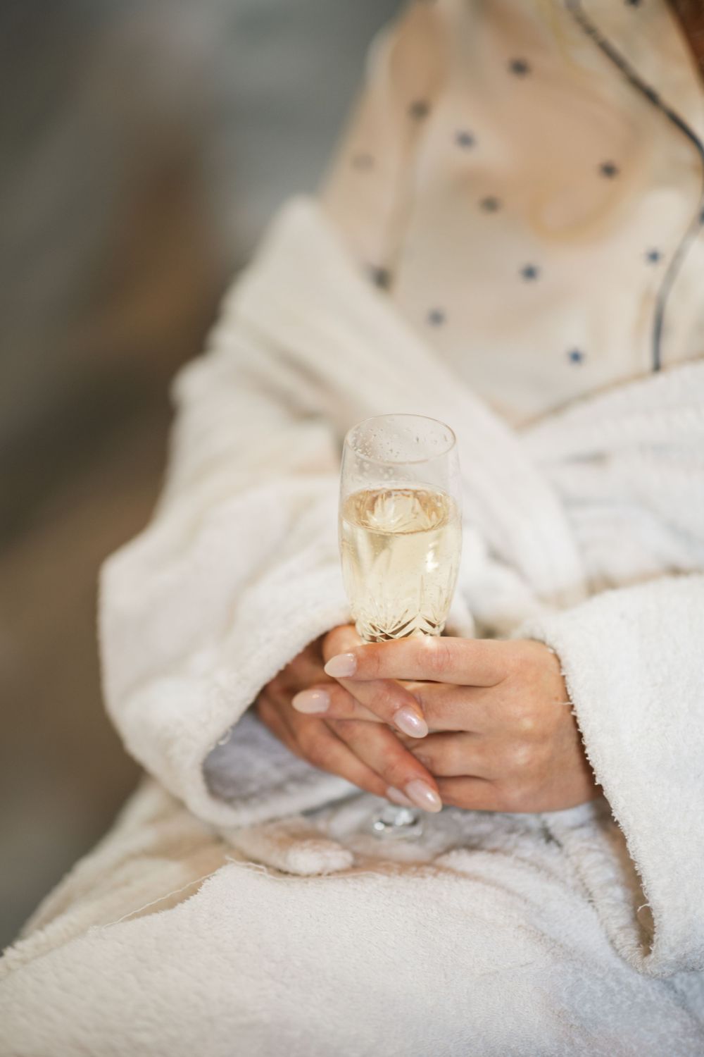 Hands holding a delicate white teacup against a soft white fabric background.