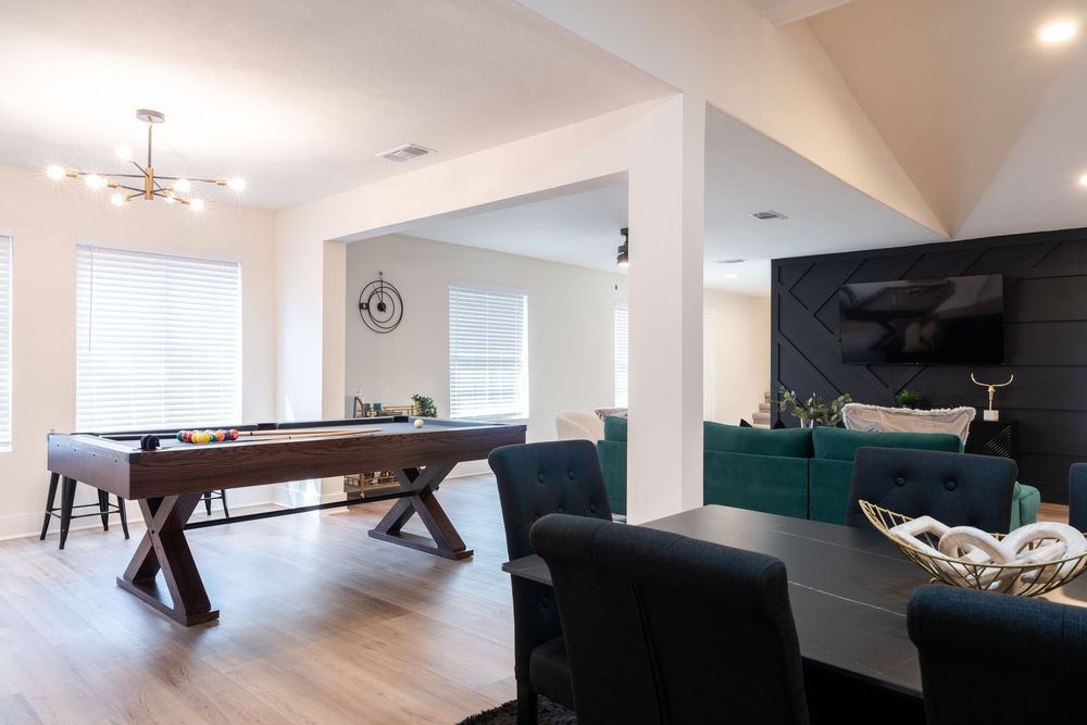 Open concept space with wooden shuffle board table and emerald green sectional sofa.