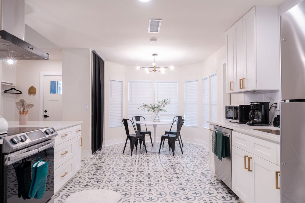 Modern white kitchen with patterned tile floor and black dining set.