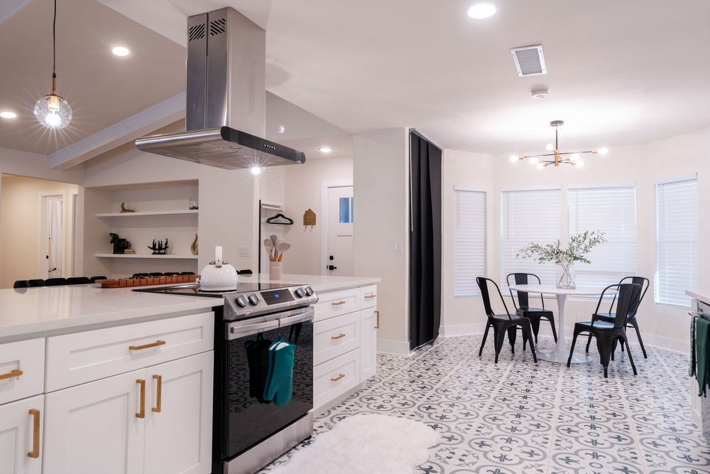 Sleek kitchen featuring white cabinets, stainless appliances and patterned floor tiles.