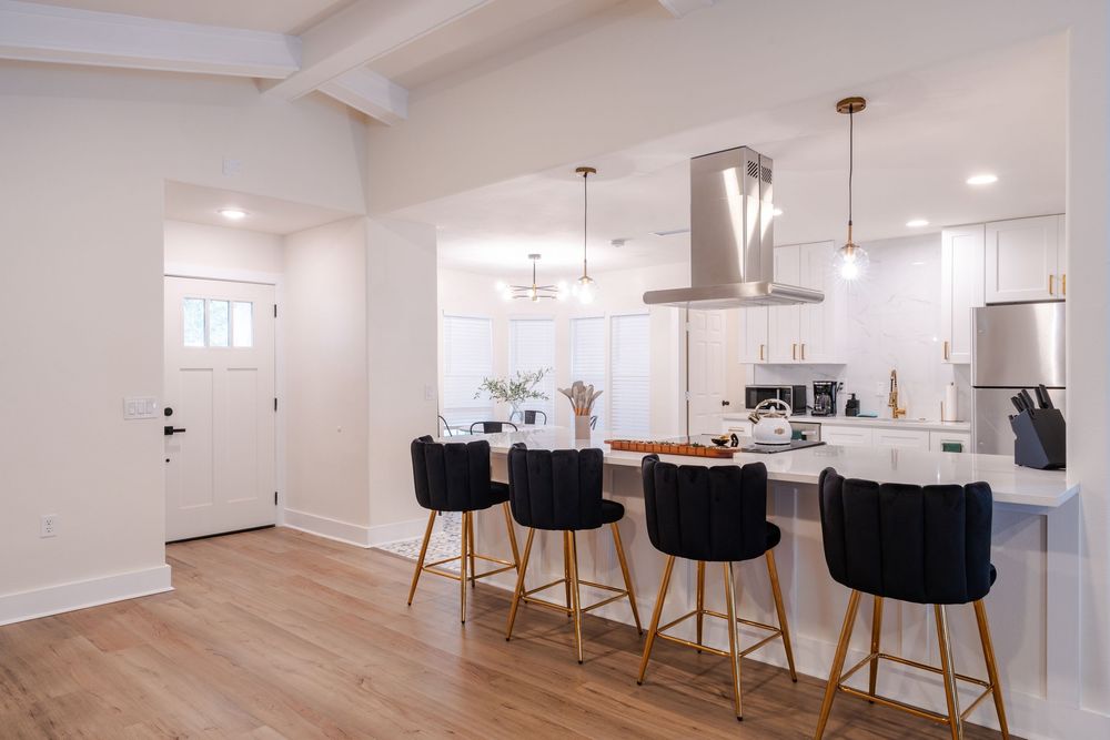 Modern kitchen with black barstools and pendant lighting in open concept layout.
