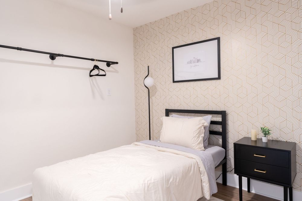 Minimalist bedroom interior with white walls, track lighting, and simple decor.