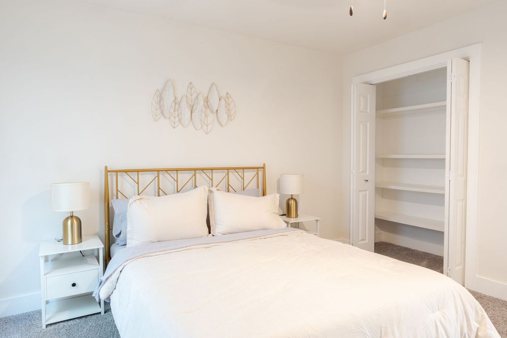 Clean white bedroom with built-in shelving and modern light fixtures.