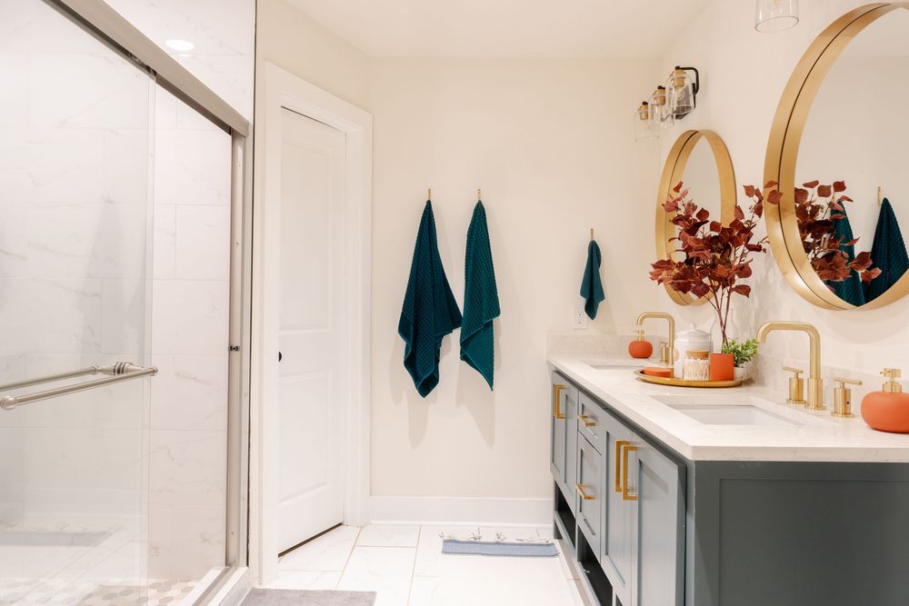 Bright bathroom interior with gold fixtures, teal accents, and decorative wall elements.