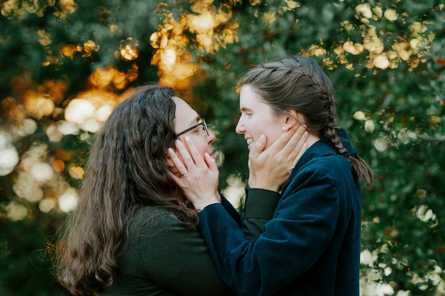 A romantic couple embraces in a garden setting with golden sunlight filtering through trees and bokeh effects.
