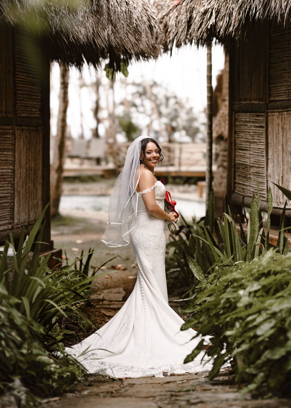 Elegant bridal portraits showing a lace wedding dress with train in a rustic outdoor setting.