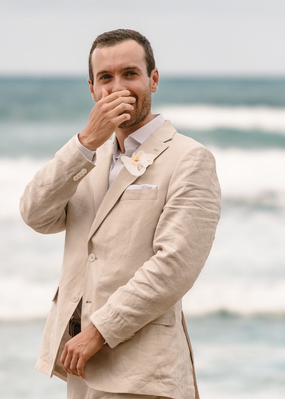 Series of candid moments showing someone in a beige suit laughing near the ocean shoreline.