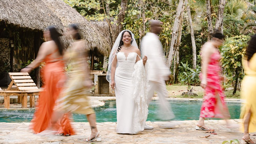 Motion blur photo of wedding party dancing around bride by pool.