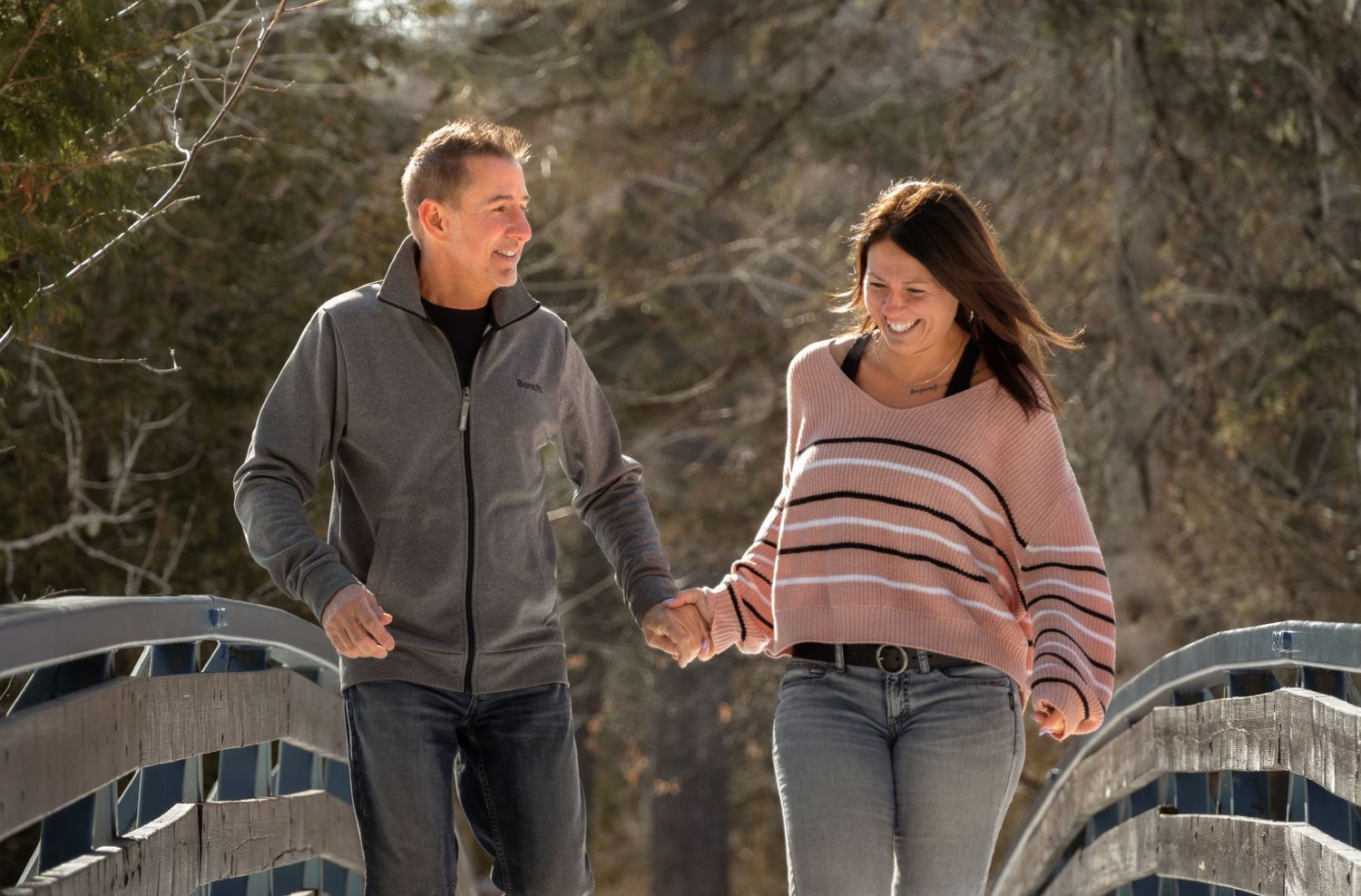 Black and white photo of couple laughing together in rustic field setting.