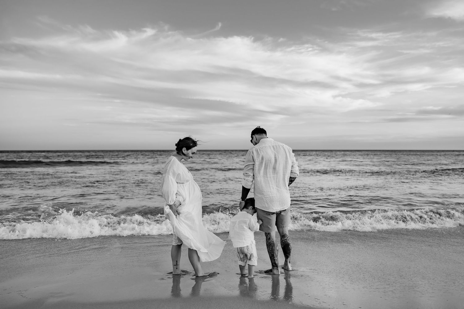 A joyful black and white candid photo of a parent and child sharing a loving embrace on sandy beach terrain.