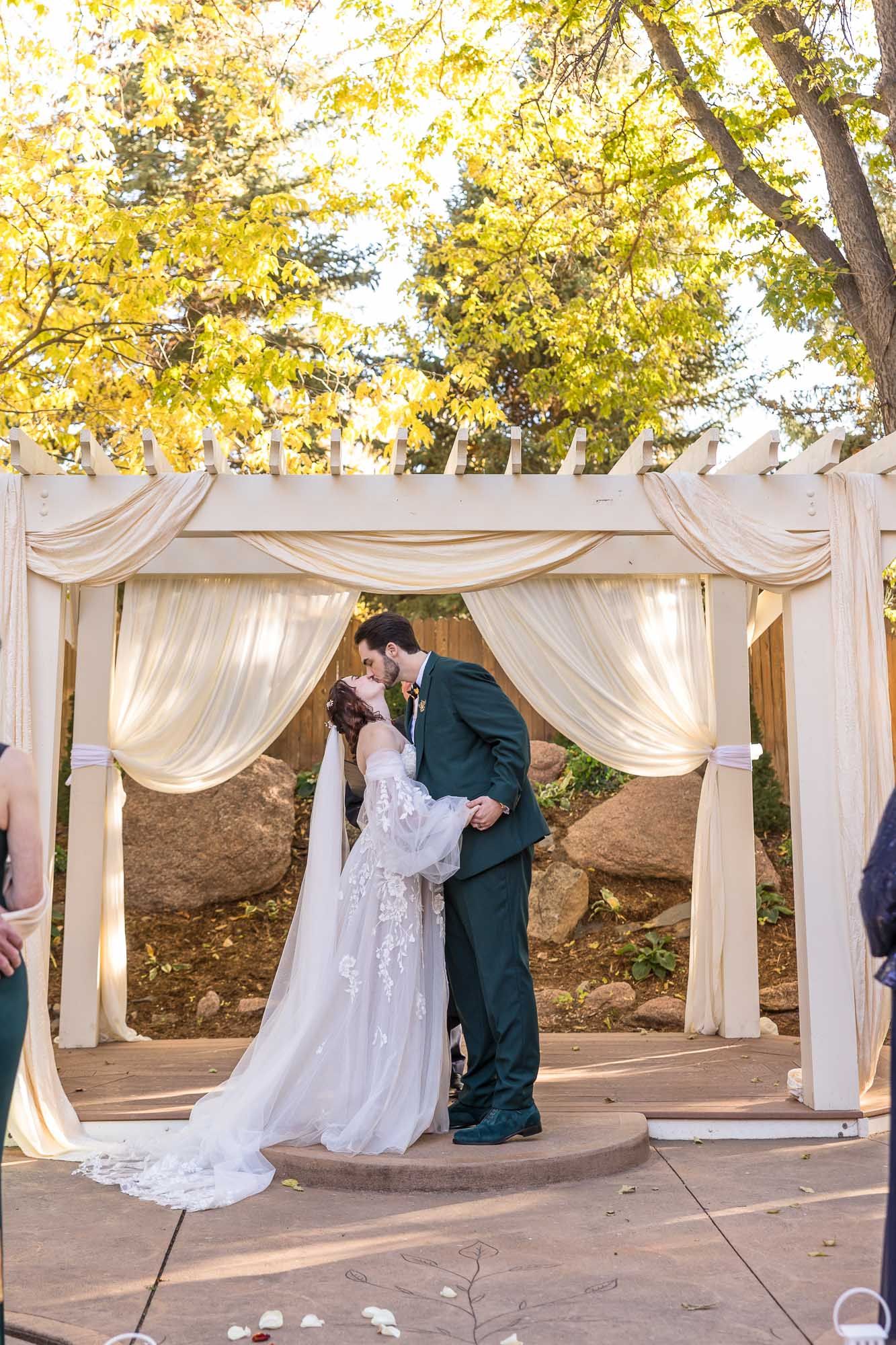 Wedding ceremony setup with flowing white fabric draping and golden autumn trees creating a romantic outdoor backdrop.