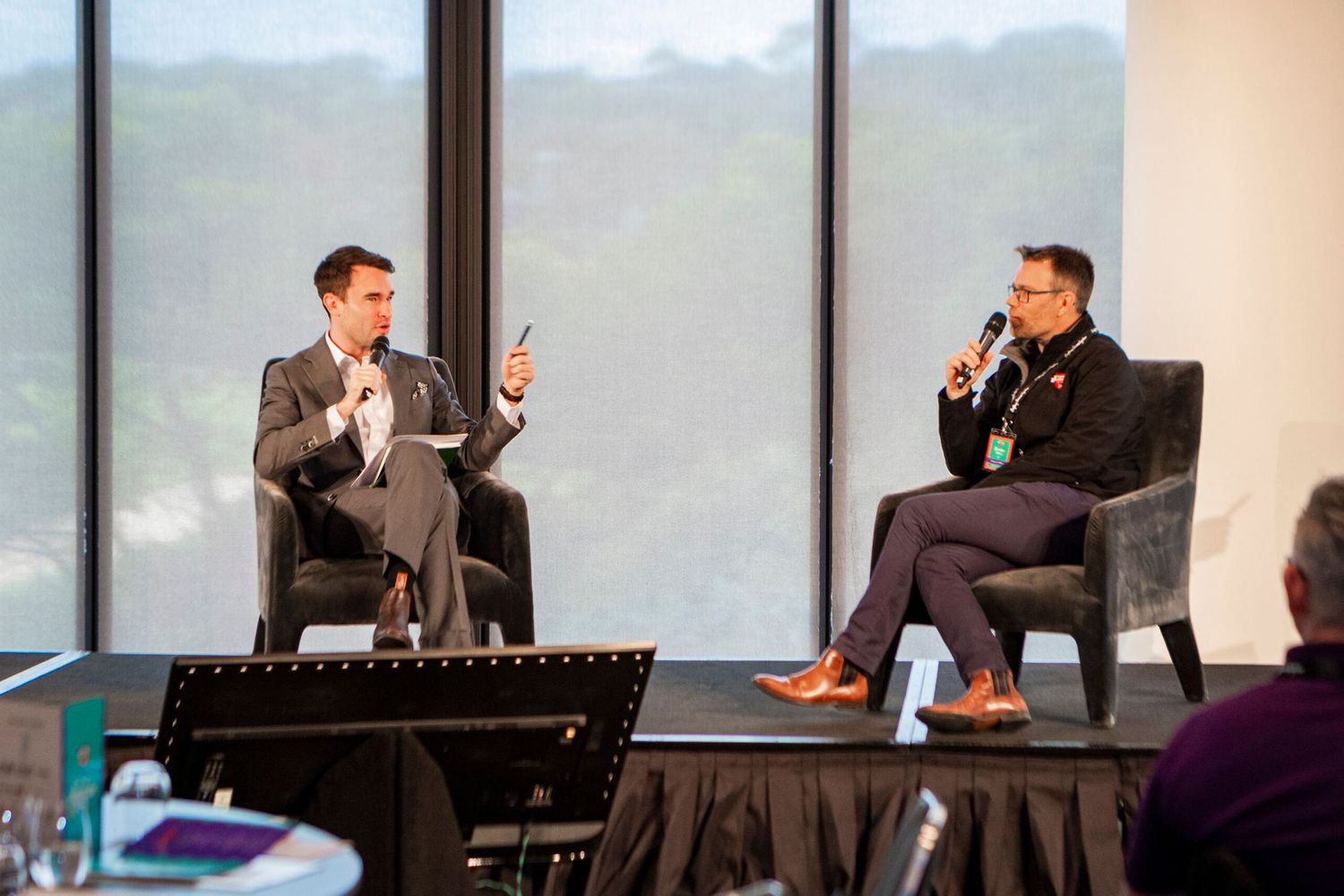 Two speakers engage in conversation during a professional conference panel discussion.