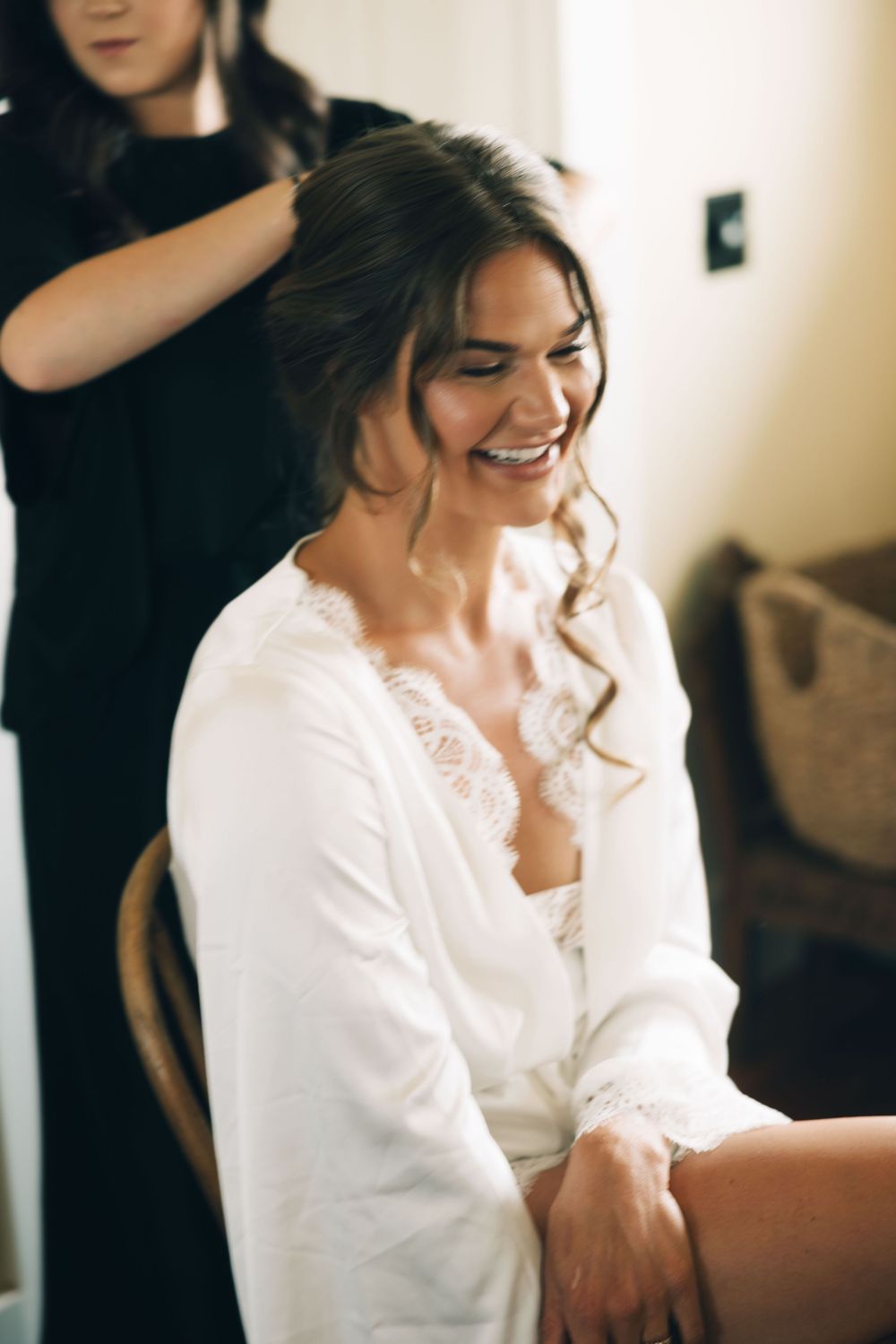 A white satin robe with lace trim being worn during wedding preparations.