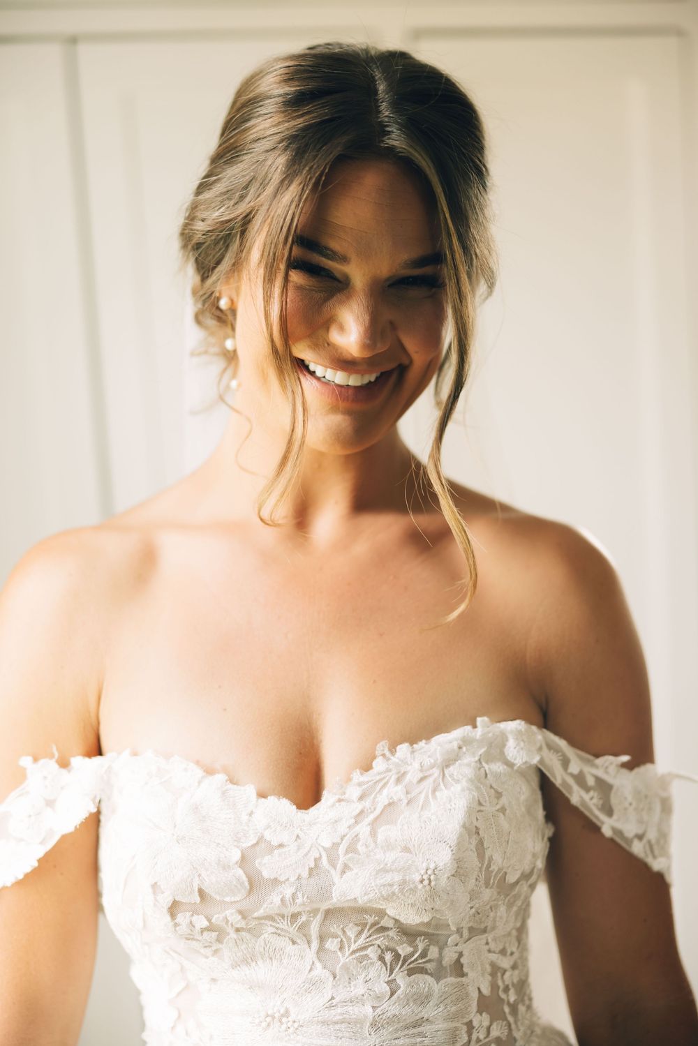 A detailed view of an off-shoulder white lace wedding gown with intricate floral patterns.