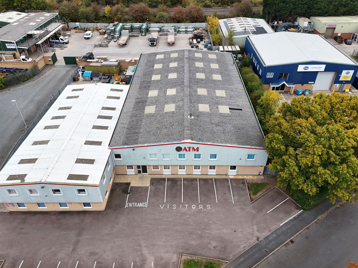 Aerial view of commercial warehouse buildings with white roofs and parking lots in an industrial area.