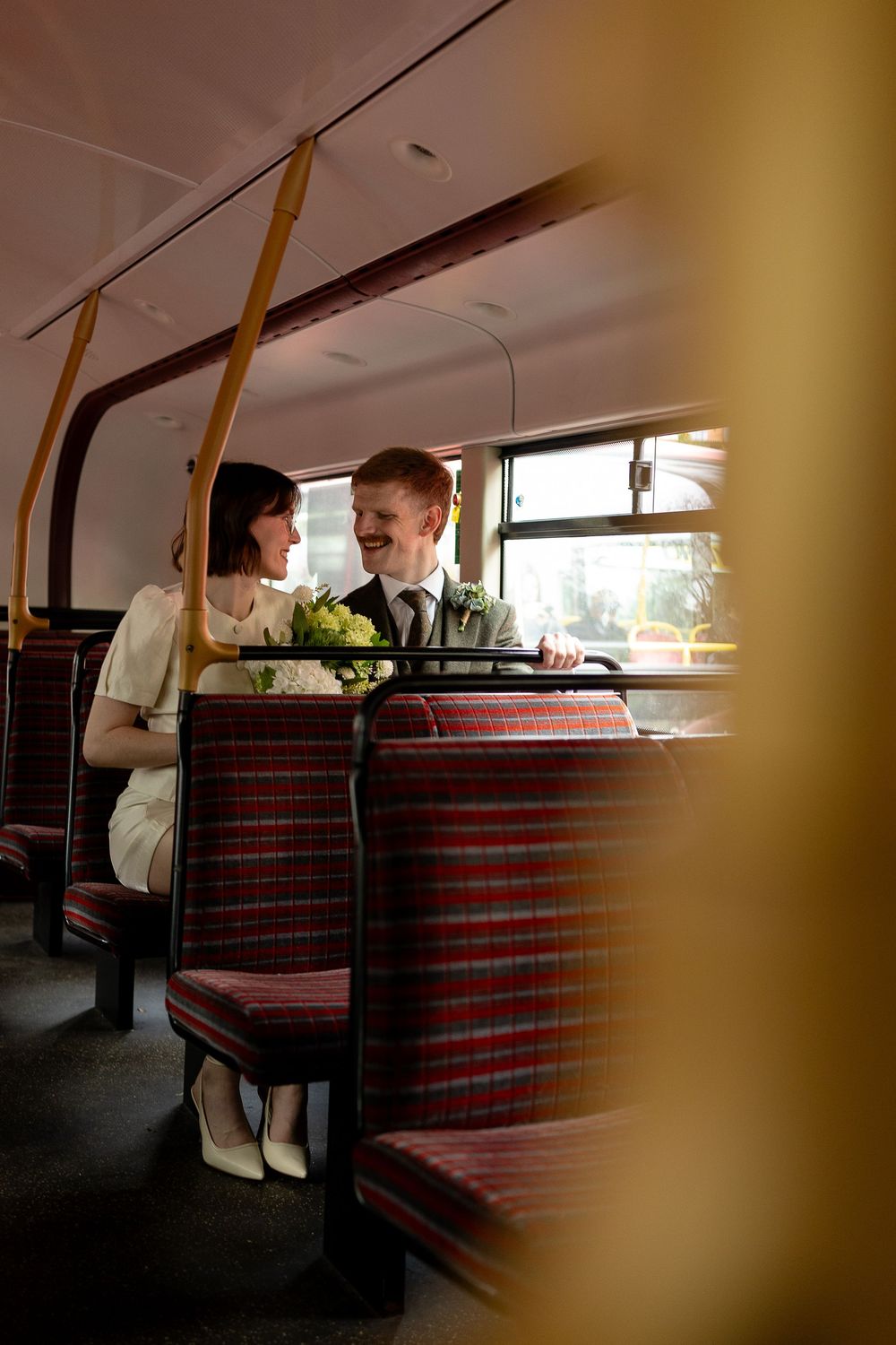 Interior of a vintage train car with red striped seats and passengers sitting by the window.