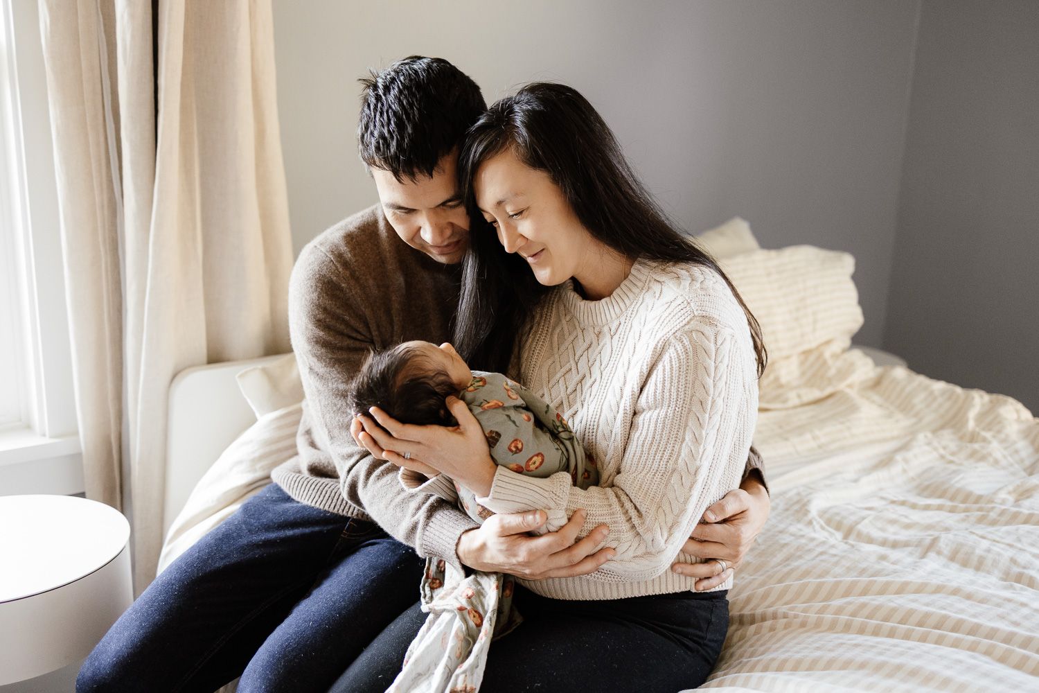 A dad and mom cradle their baby at an in-home newborn photoshoot