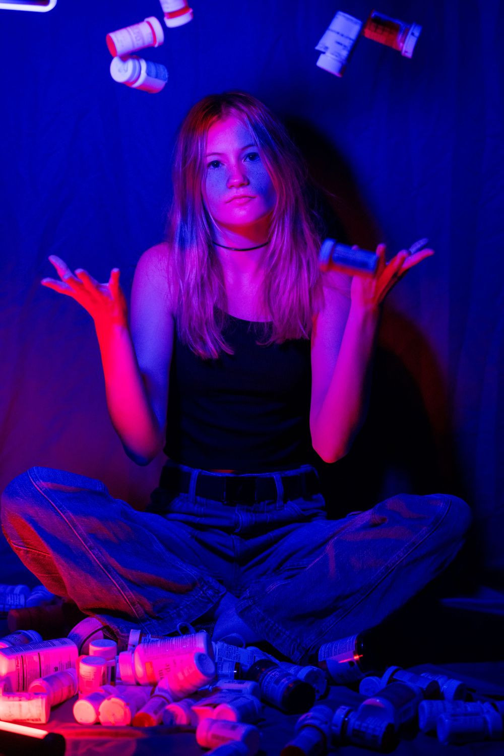 Person in dark room illuminated by dramatic red lighting arranges small objects in a mystical setup.