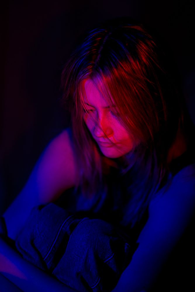 Artistic portrait with dramatic lighting featuring vibrant blue and red neon colors creating a moody atmosphere.