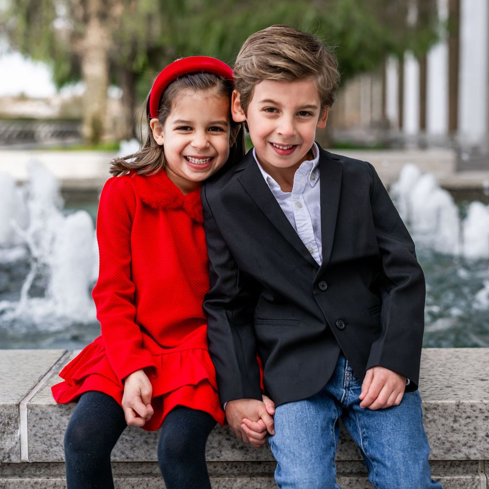 Siblings joyfully playing on the grounds of the Kennedy Center during a family photo session.