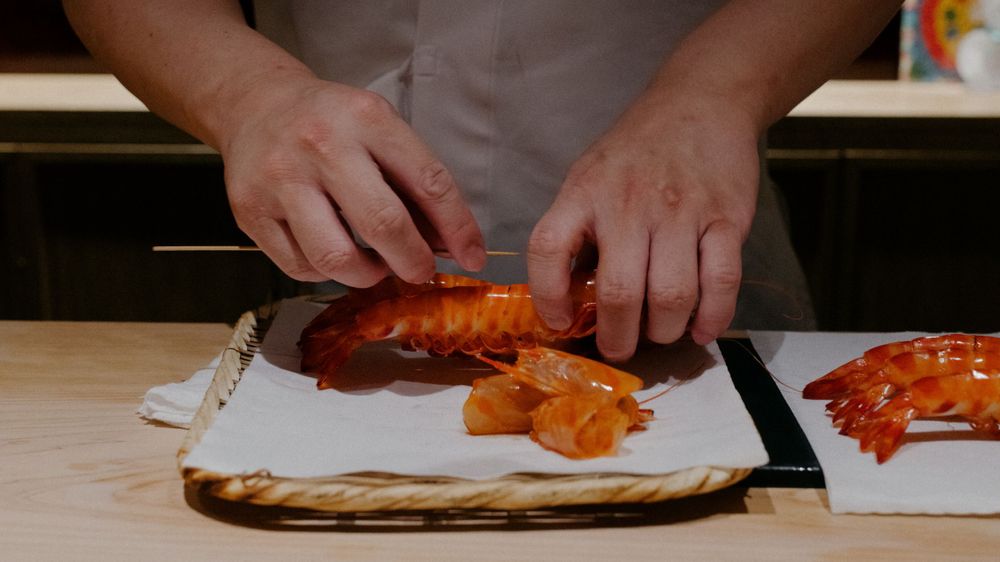 Hands skillfully cutting and preparing fresh seafood on a white cutting board.