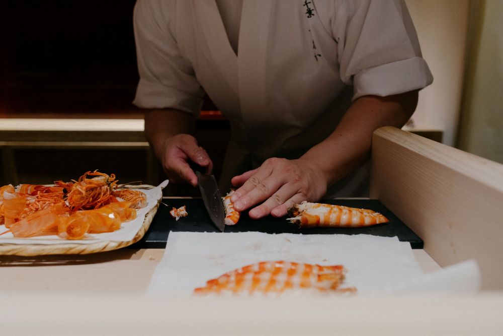 Chef preparing sushi at a counter with fresh seafood ingredients.