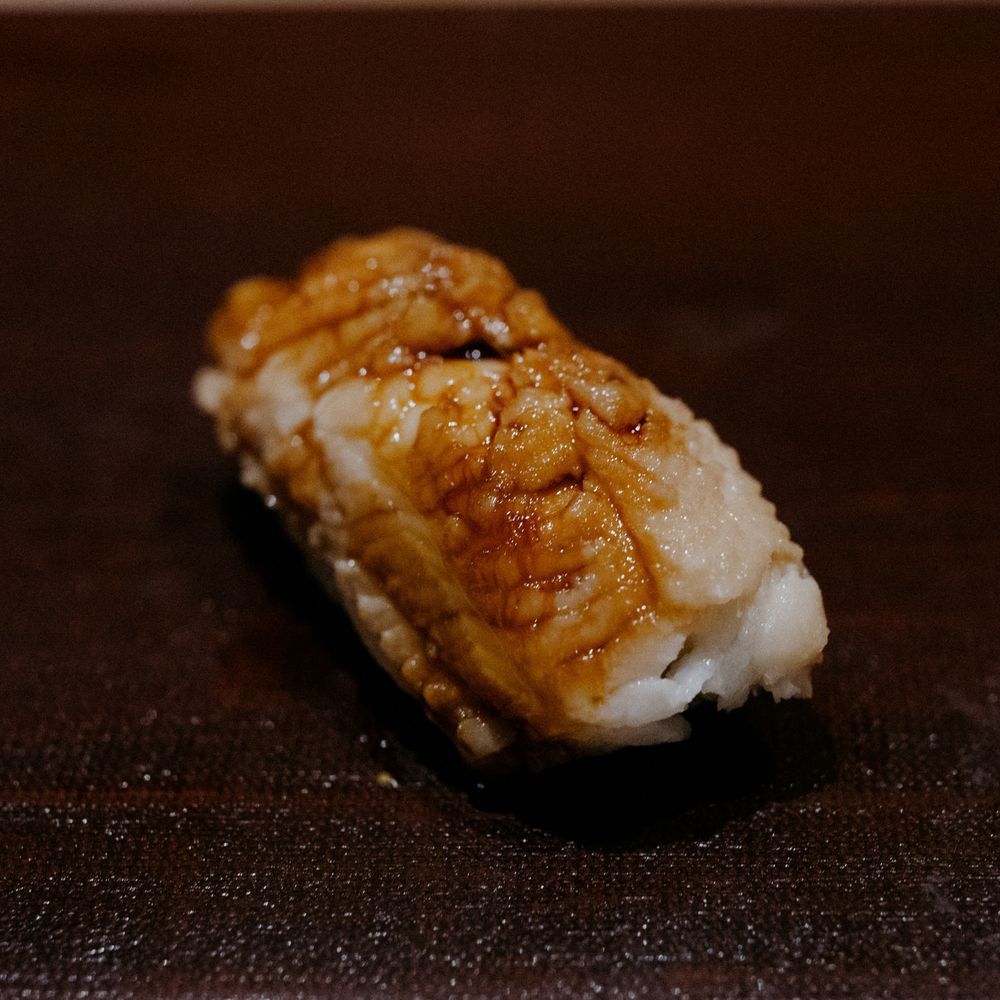 Close-up of aburi style nigiri sushi with caramelized topping and visible char marks.