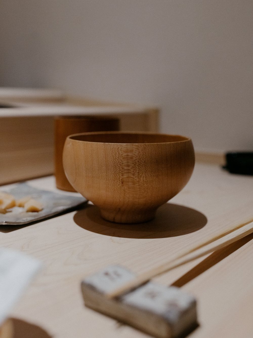 Traditional wooden Japanese soup bowl on a white table setting.