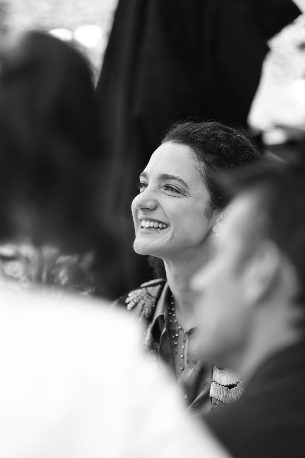 A black and white candid photo showing a joyful smile in a crowded setting.