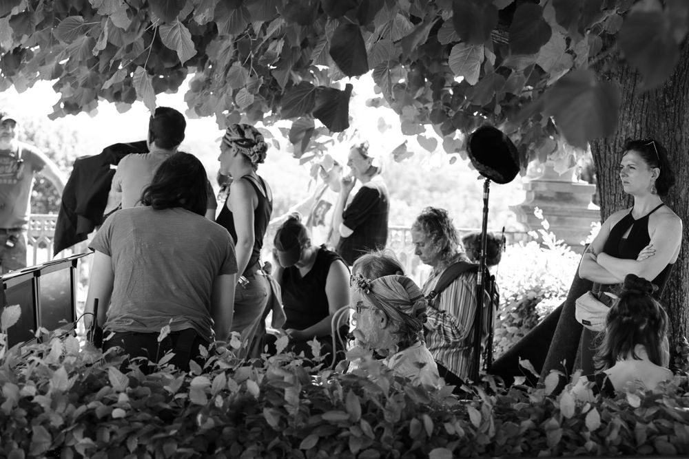 A black and white image showing people gathered under tree foliage.