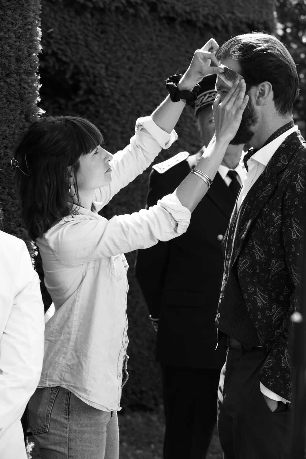 Black and white photo of someone styling hair during a professional photoshoot or filming session.