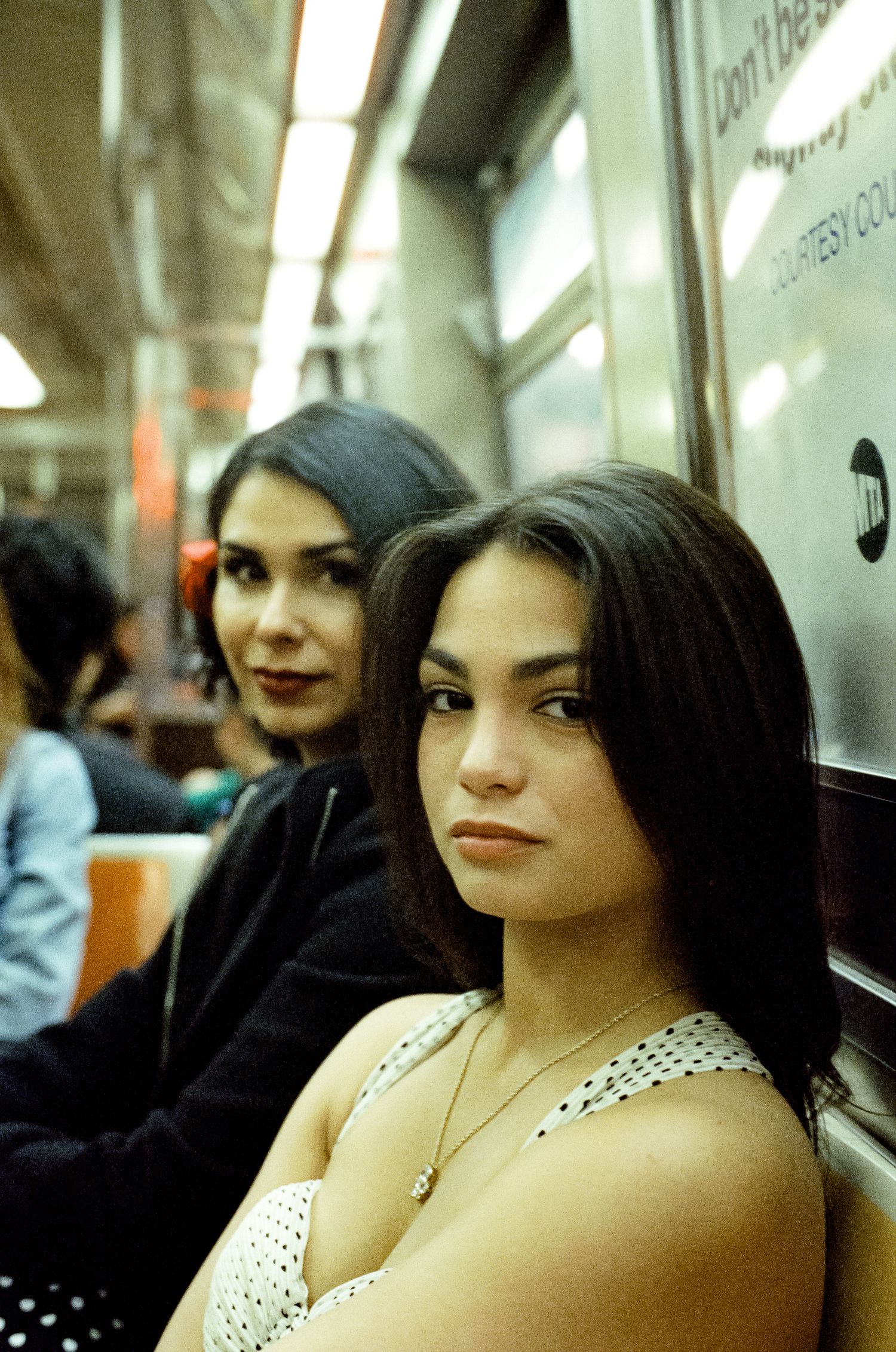 Two passengers sitting together on public transit in an illuminated subway car.
