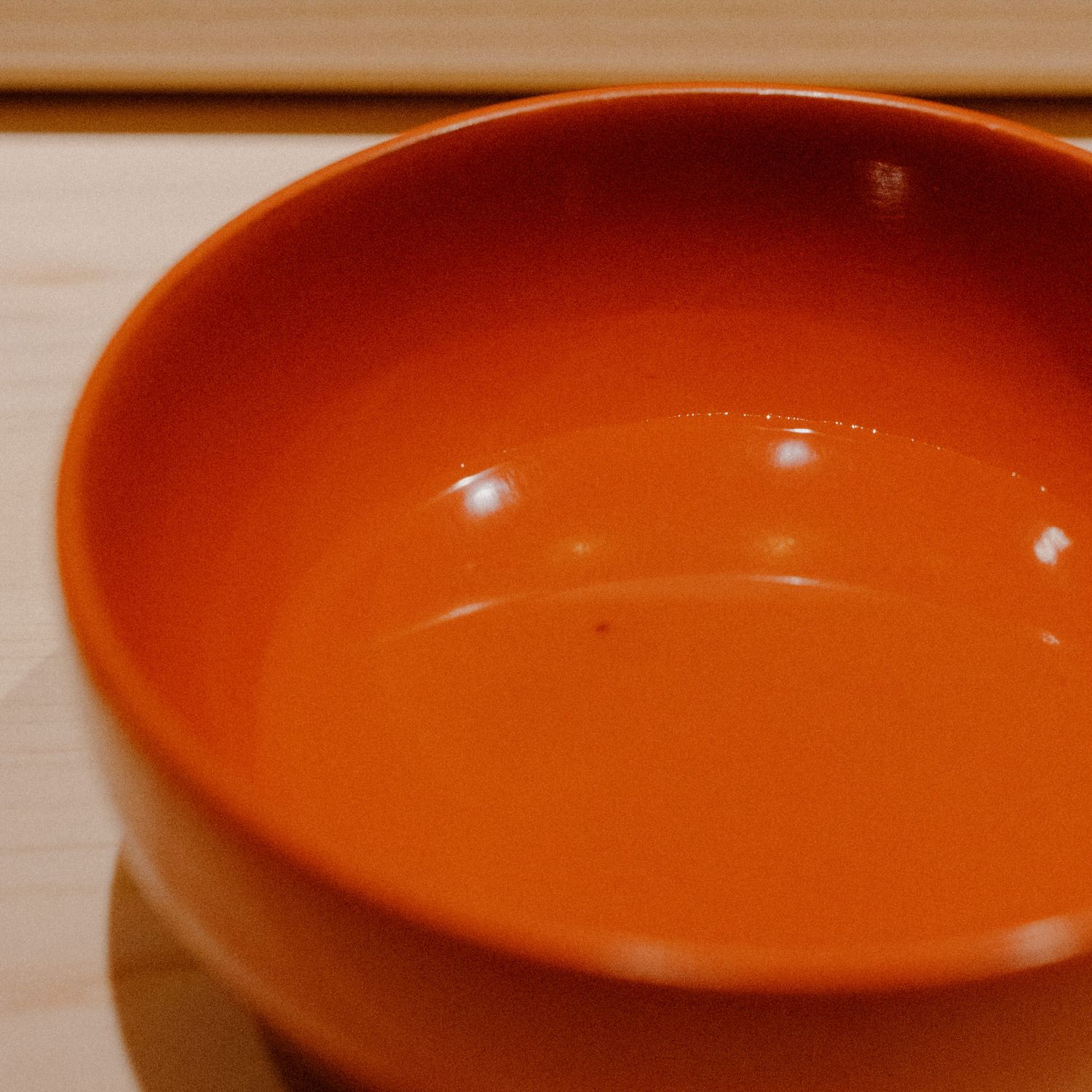 Close-up of an empty orange ceramic bowl on a wooden surface.